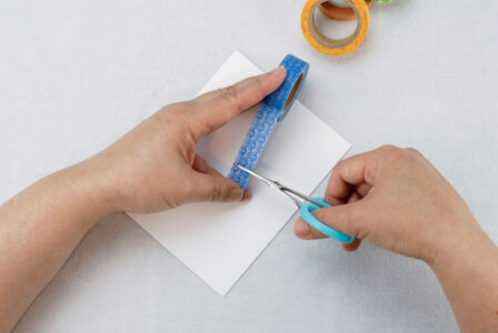 person using scissors to cut blue craft tape